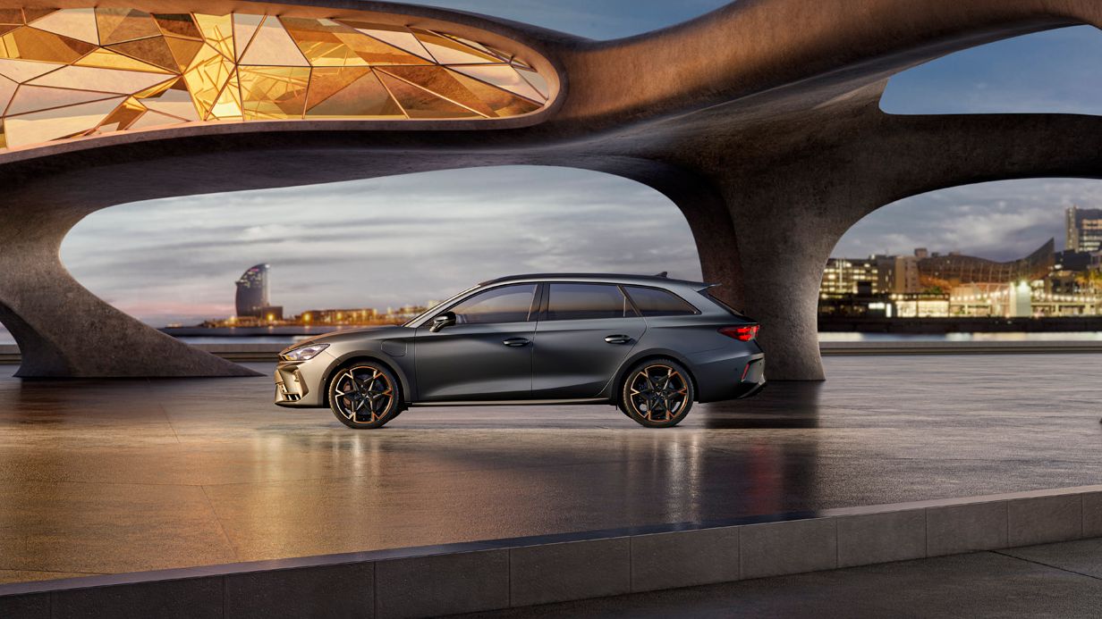 Seitenansicht eines grauen CUPRA Leon SP Kombi, der in einem modernen Parkhaus parkt.