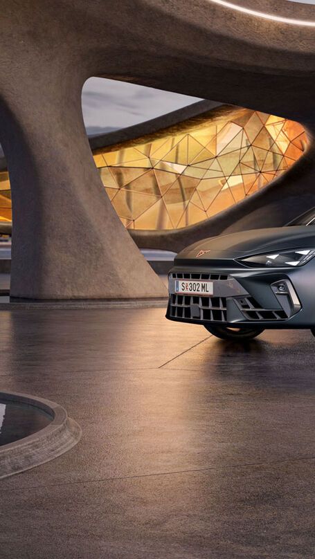 Schräge Vorderansicht eines grauen CUPRA Leon SP Kombi, der in einem modernen Parkhaus parkt.