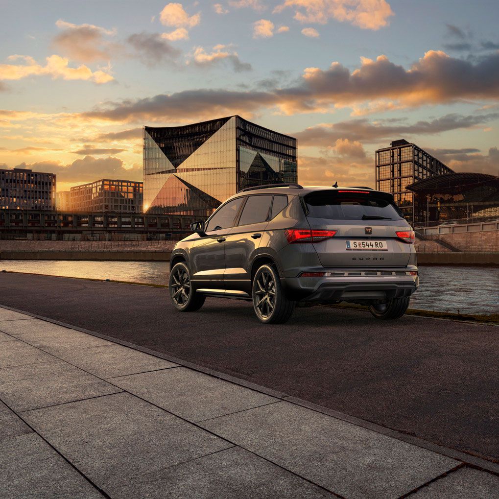 Heckansicht des CUPRA Ateca SUVs bei Sonnenuntergang, mit Fokus auf den neuen, niedrigeren Frontgrill mit Luftkappen und den neuen Heckdiffusor, die beide das äußere Design verstärken und die Aerodynamik optimieren.