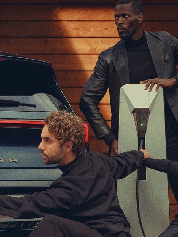 Zwei CUPRA Born links und rechts neben einer Ladesäule, eine Gruppe Tänzer posiert vor den Fahrzeugen.