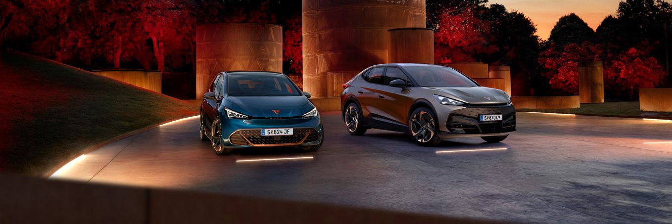 CUPRA Born und Tavascan stehen nebeneinander auf beleuchtetem hintergrund