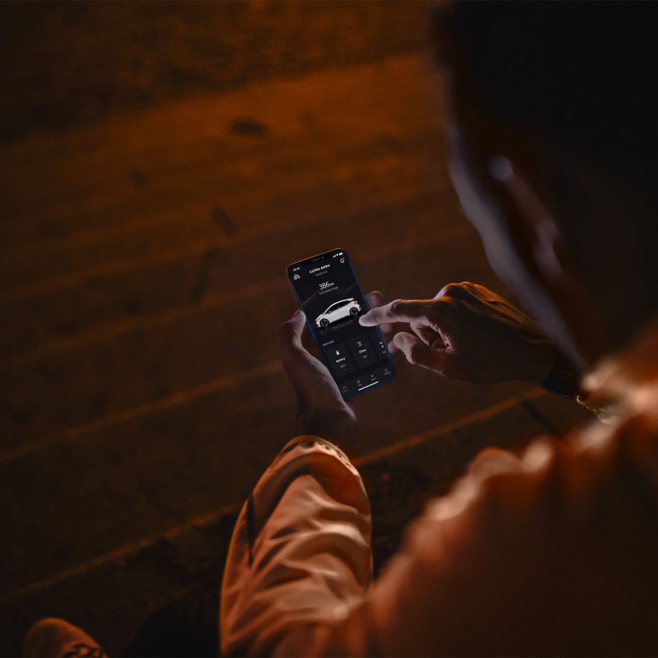 Eine Person sitzt nachts auf Treppenstufen und nutzt CUPRA Connect auf einem Smartphone.