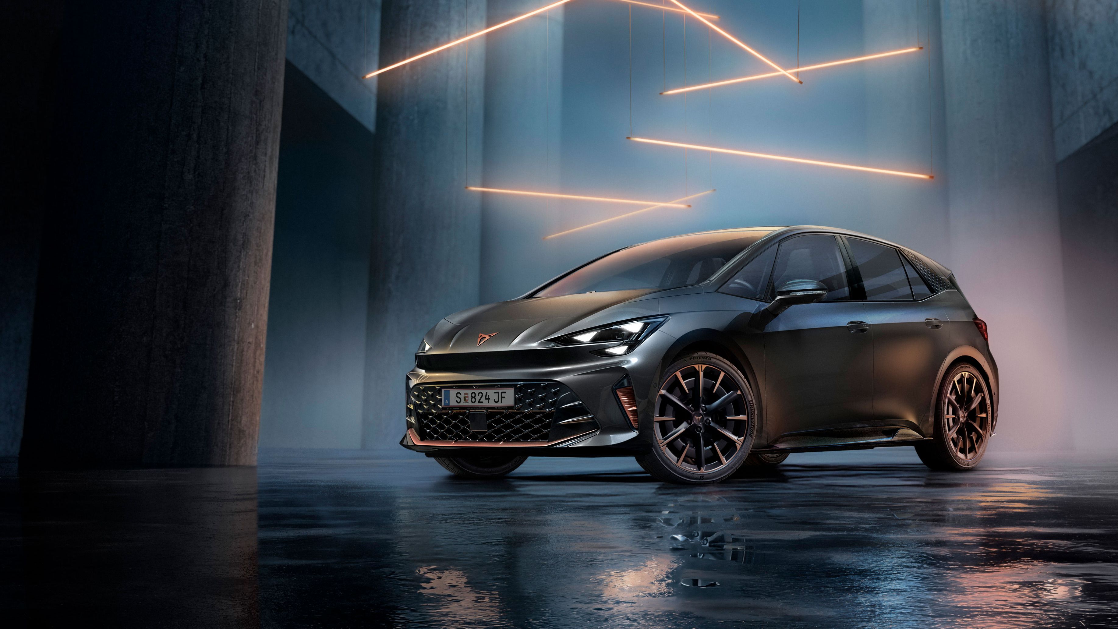 Ein grauer CUPRA Born steht in einer modernen, dunklen Umgebung mit vertikalen Säulen und leuchtenden LED-Streifen. Der Boden ist glänzend und reflektiert das Fahrzeug sowie die Beleuchtung. Das Auto wirkt kraftvoll und elegant.