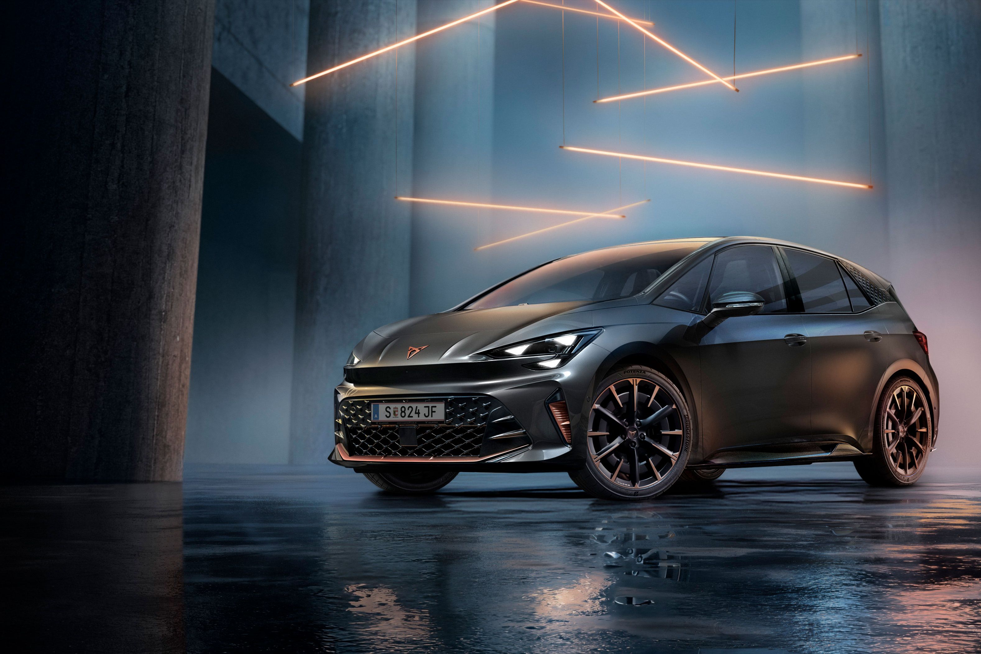 Ein grauer CUPRA Born steht in einer modernen, dunklen Umgebung mit vertikalen Säulen und leuchtenden LED-Streifen. Der Boden ist glänzend und reflektiert das Fahrzeug sowie die Beleuchtung. Das Auto wirkt kraftvoll und elegant.