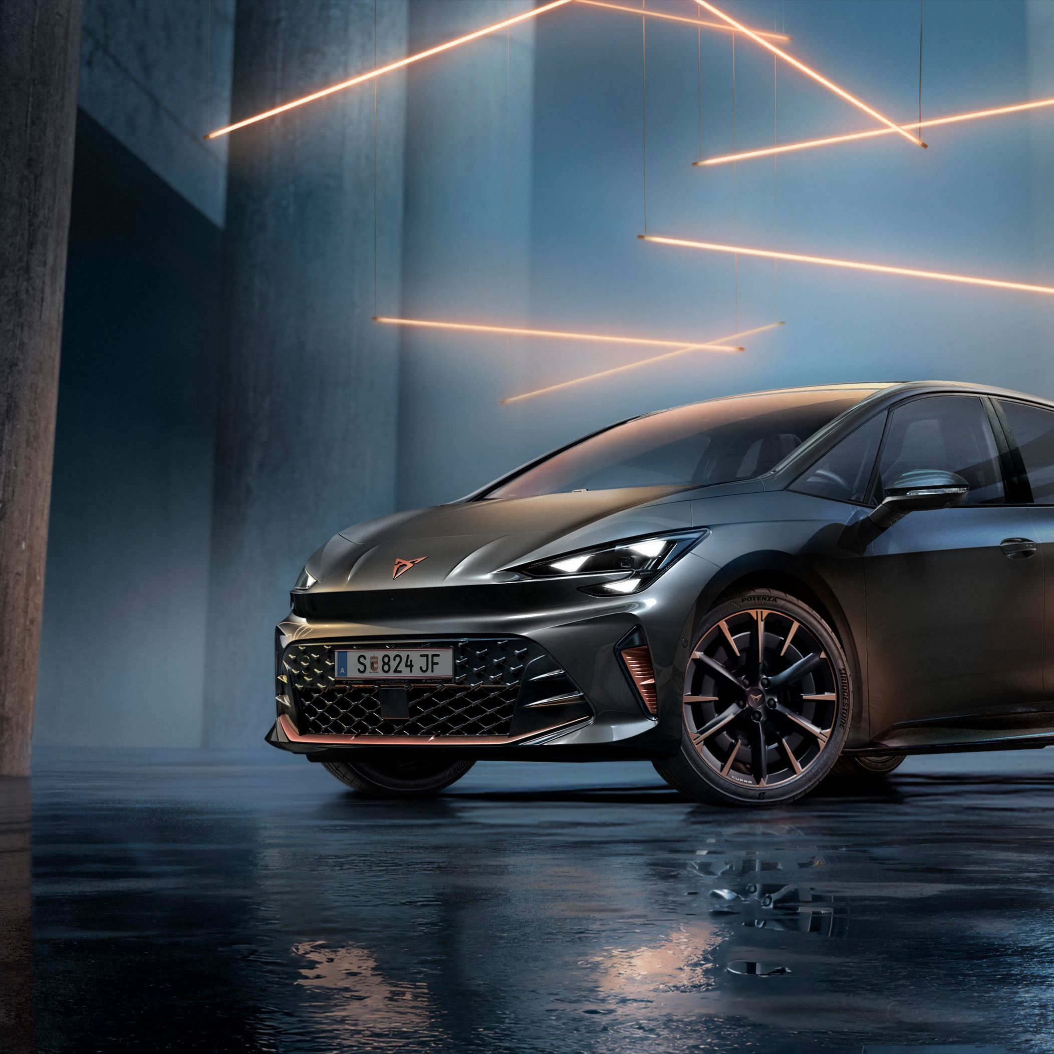 Ein grauer CUPRA Born steht in einer modernen, dunklen Umgebung mit vertikalen Säulen und leuchtenden LED-Streifen. Der Boden ist glänzend und reflektiert das Fahrzeug sowie die Beleuchtung. Das Auto wirkt kraftvoll und elegant.