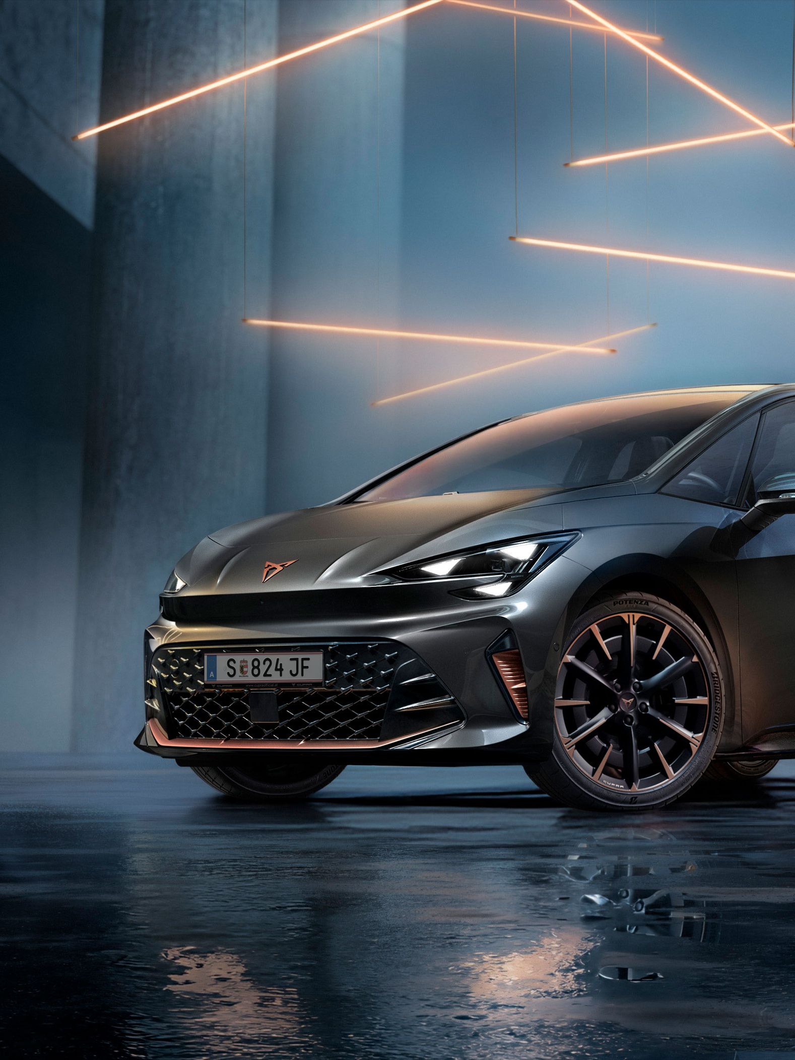 Ein grauer CUPRA Born steht in einer modernen, dunklen Umgebung mit vertikalen Säulen und leuchtenden LED-Streifen. Der Boden ist glänzend und reflektiert das Fahrzeug sowie die Beleuchtung. Das Auto wirkt kraftvoll und elegant.