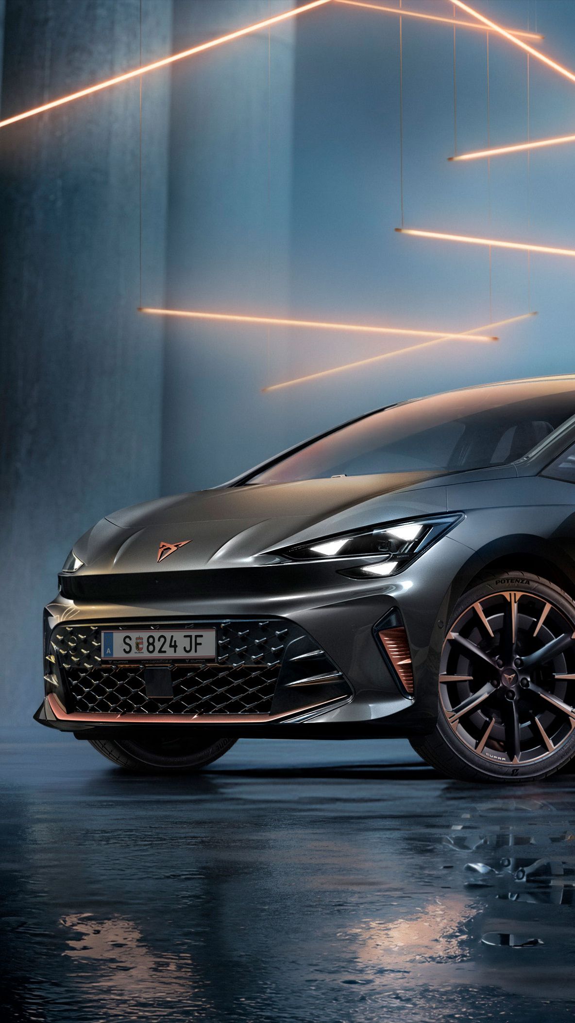 Ein grauer CUPRA Born steht in einer modernen, dunklen Umgebung mit vertikalen Säulen und leuchtenden LED-Streifen. Der Boden ist glänzend und reflektiert das Fahrzeug sowie die Beleuchtung. Das Auto wirkt kraftvoll und elegant.