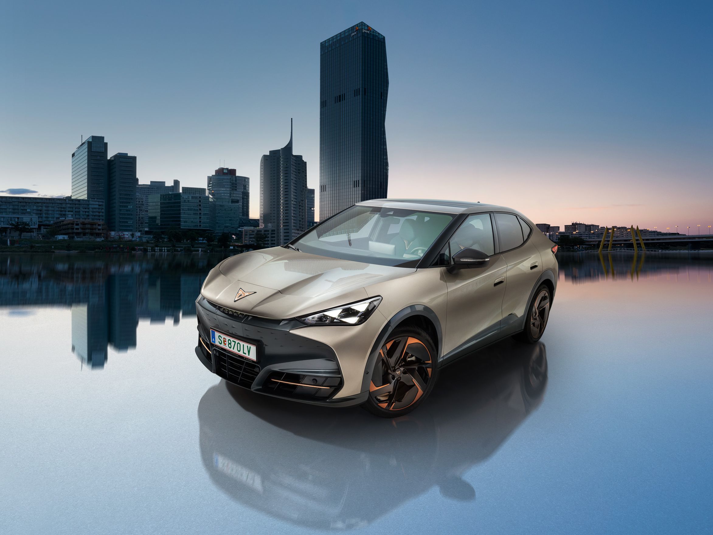 Der CUPRA Tavascan in Atacama Beige mit der Wiener Donau im Hintergrund