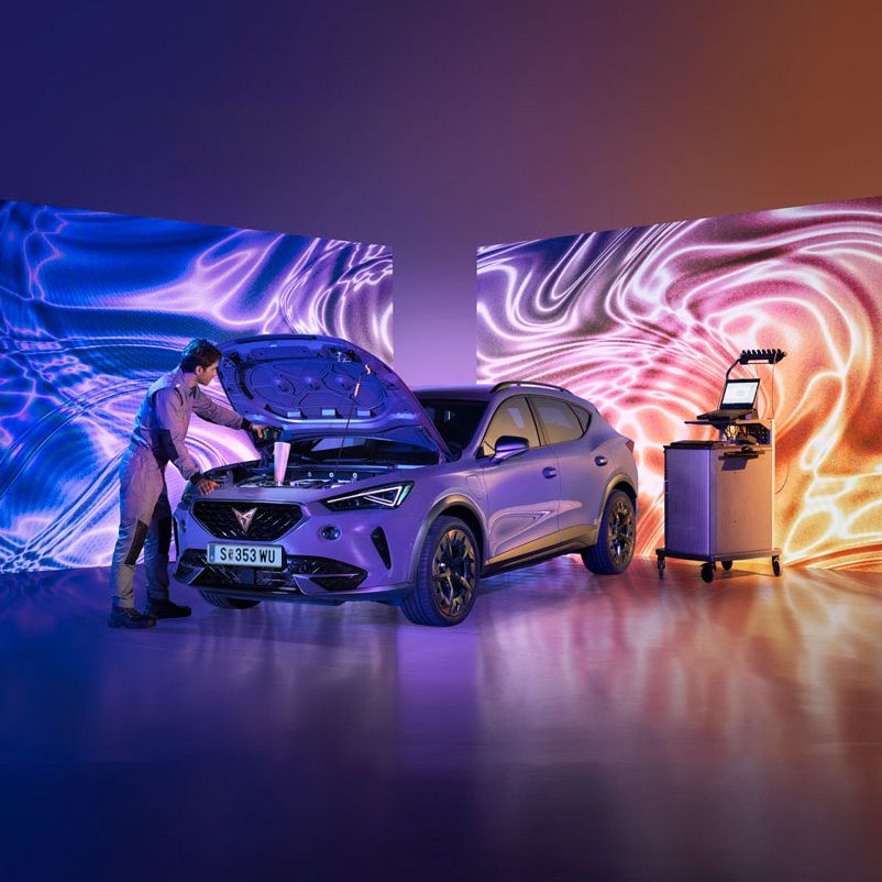 Ein CUPRA Techniker mit Diagnosegeräten öffnet die Motorhaube eines CUPRA Formentor.
