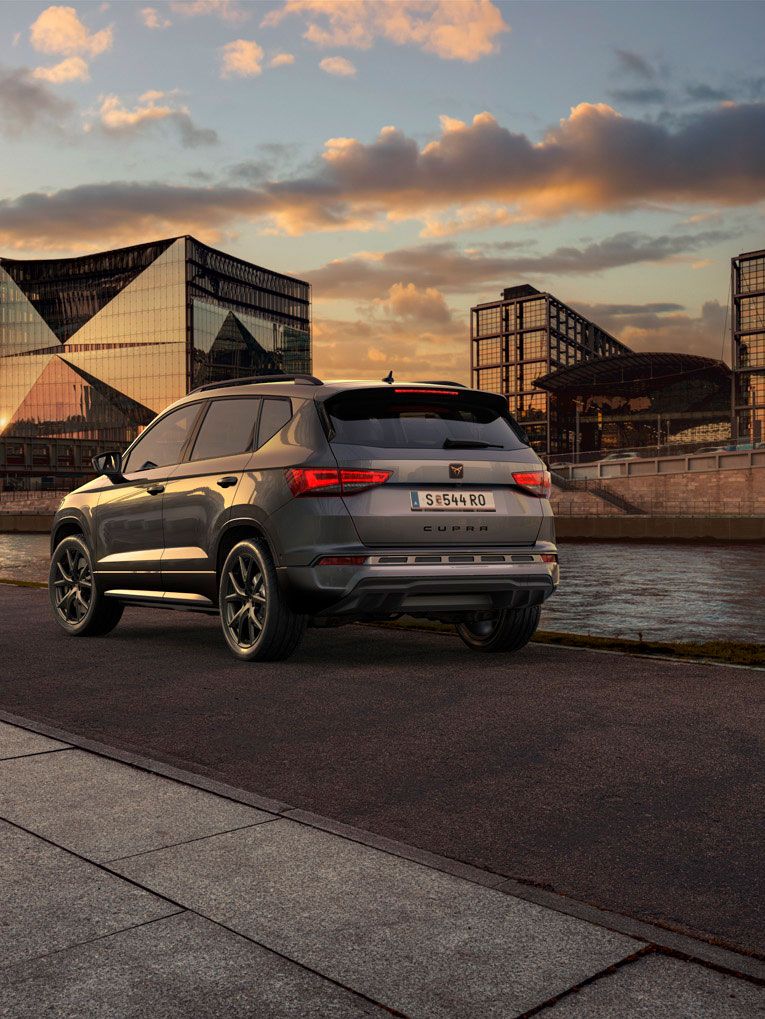 Heckansicht des CUPRA Ateca SUVs bei Sonnenuntergang, mit Fokus auf den neuen, niedrigeren Frontgrill mit Luftkappen und den neuen Heckdiffusor, die beide das äußere Design verstärken und die Aerodynamik optimieren.