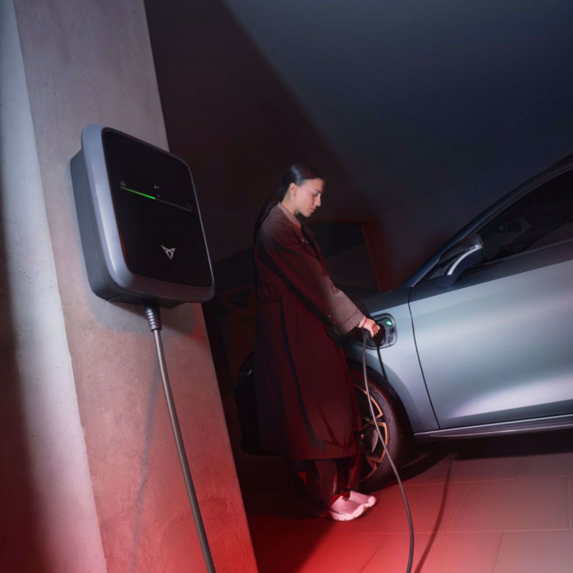 Eine Frau lädt einen grauen CUPRA Leon an einem CUPRA Charger.