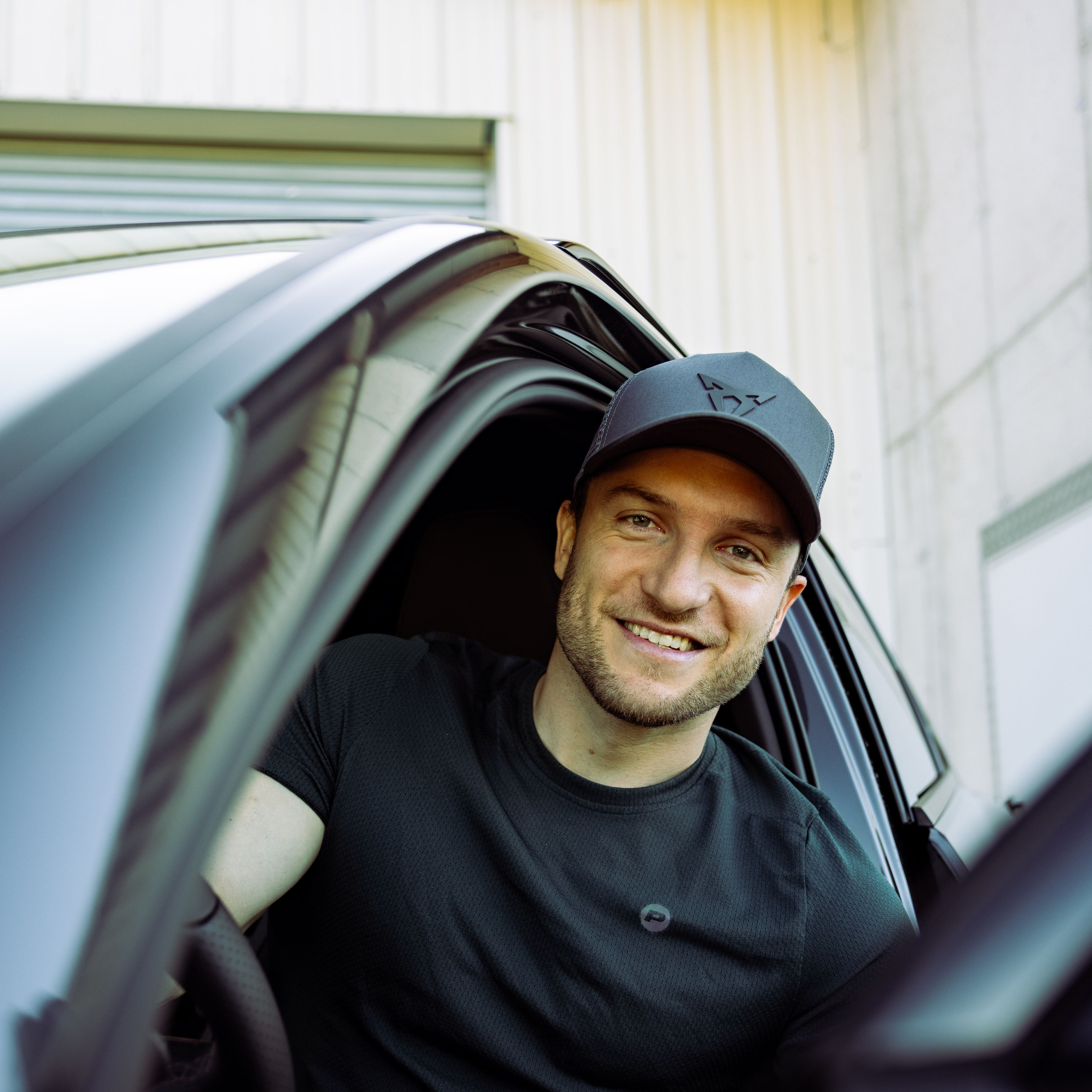 Sascha Huber im Auto mit Tür geöffnet und CUPRA Cap