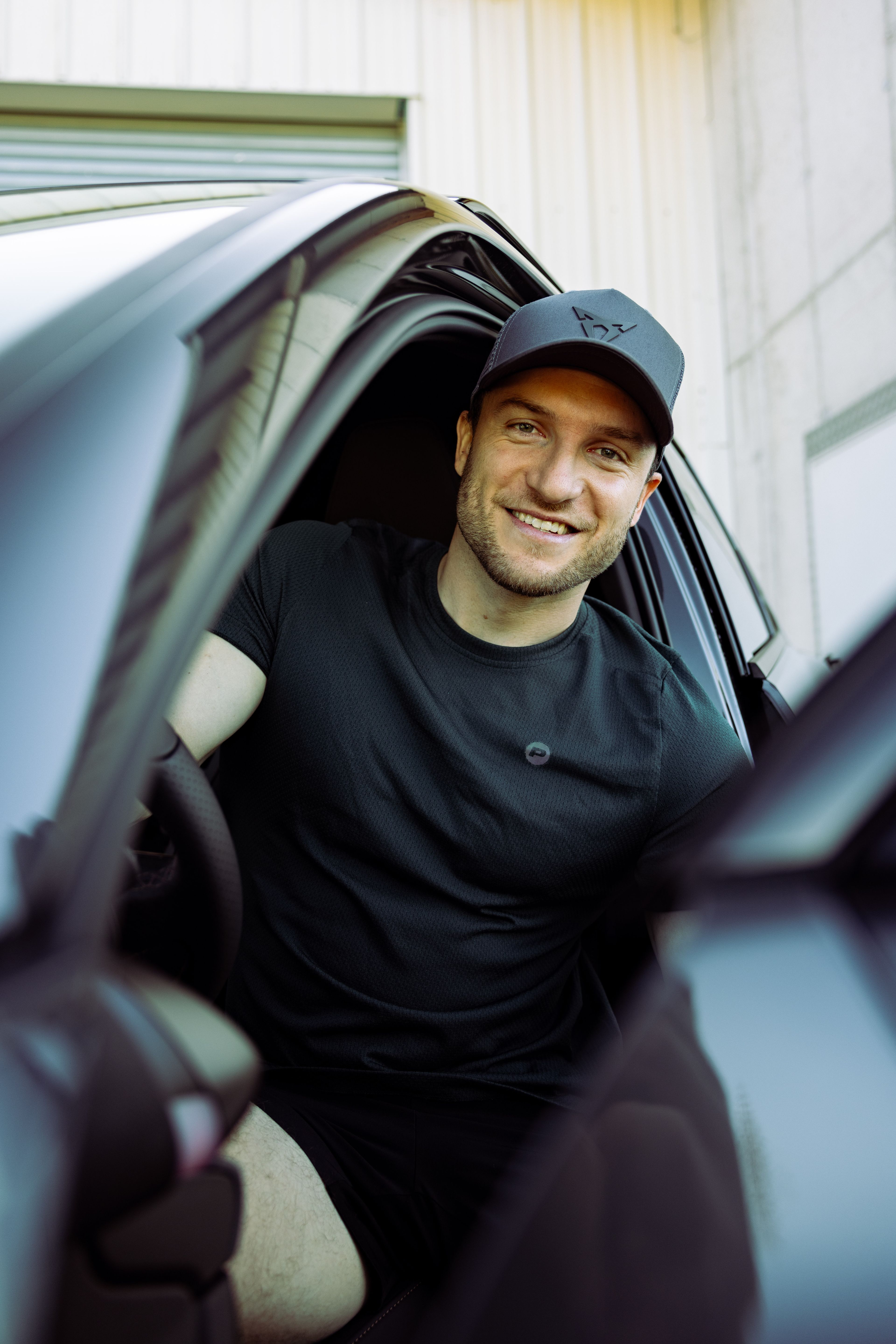 Sascha Huber im Auto mit Tür geöffnet und CUPRA Cap