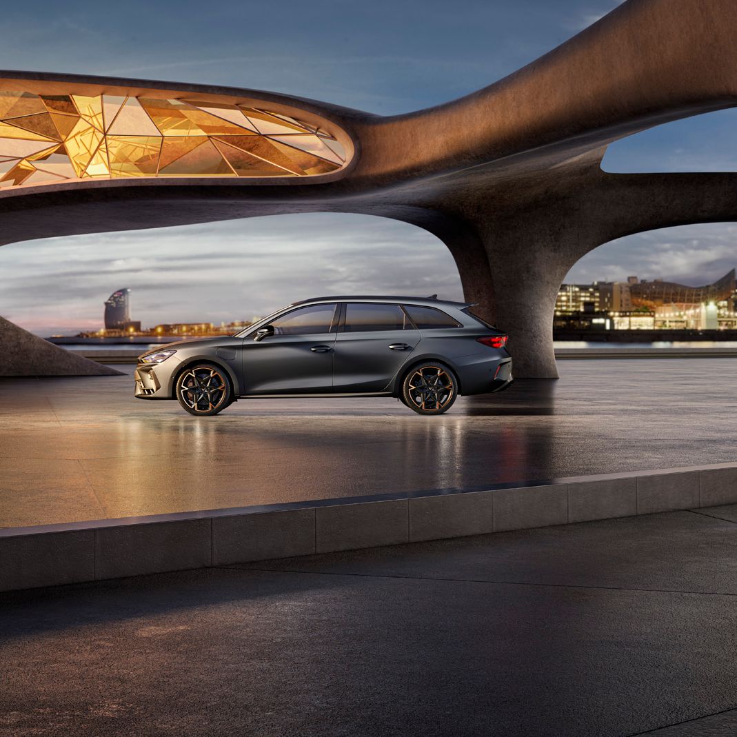 Seitenansicht eines grauen CUPRA Leon SP Kombi, der in einem modernen Parkhaus parkt.