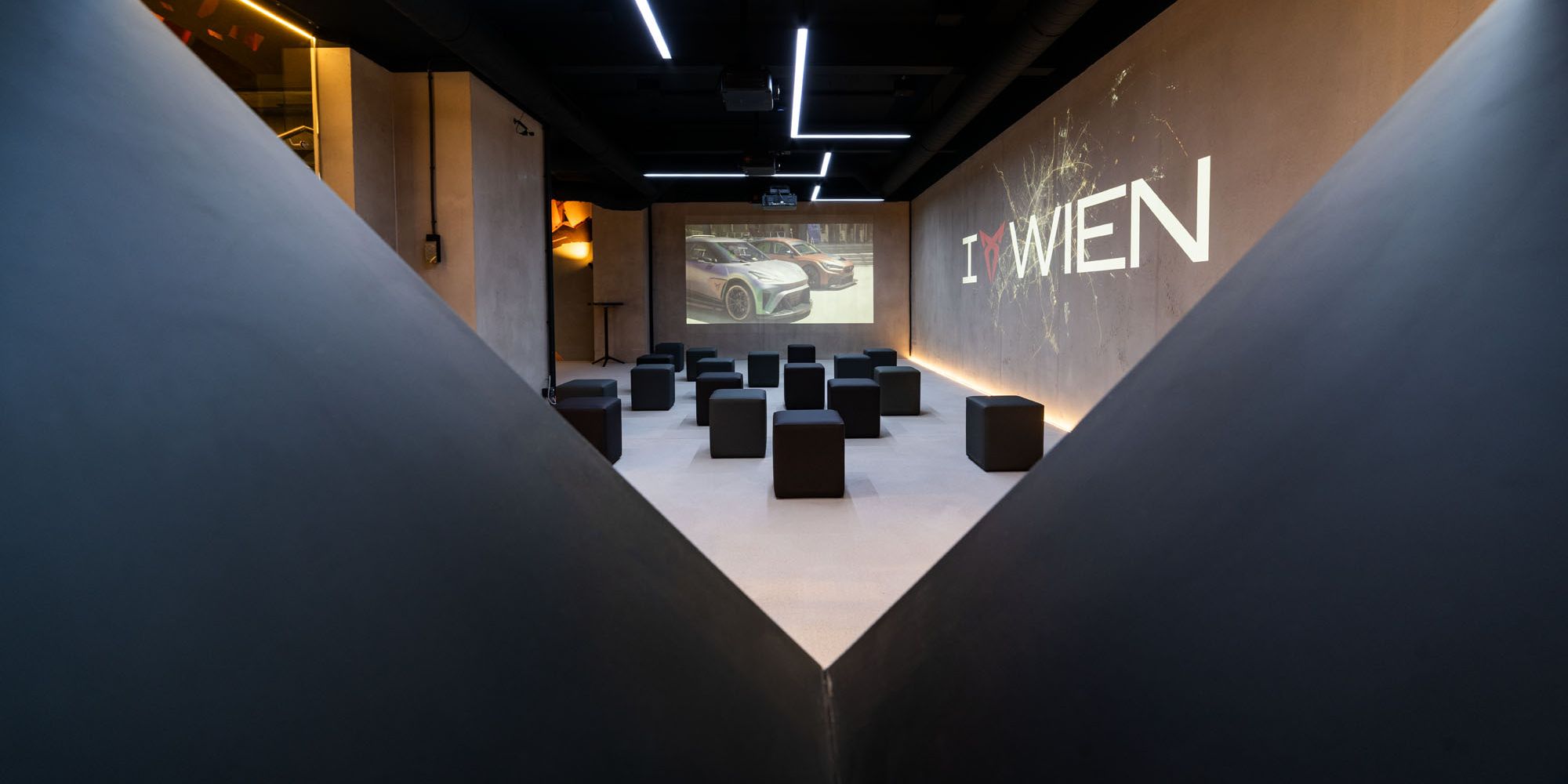 Raum mit Würfel-Sesseln und I CUPRA Wien Logo an der Wand