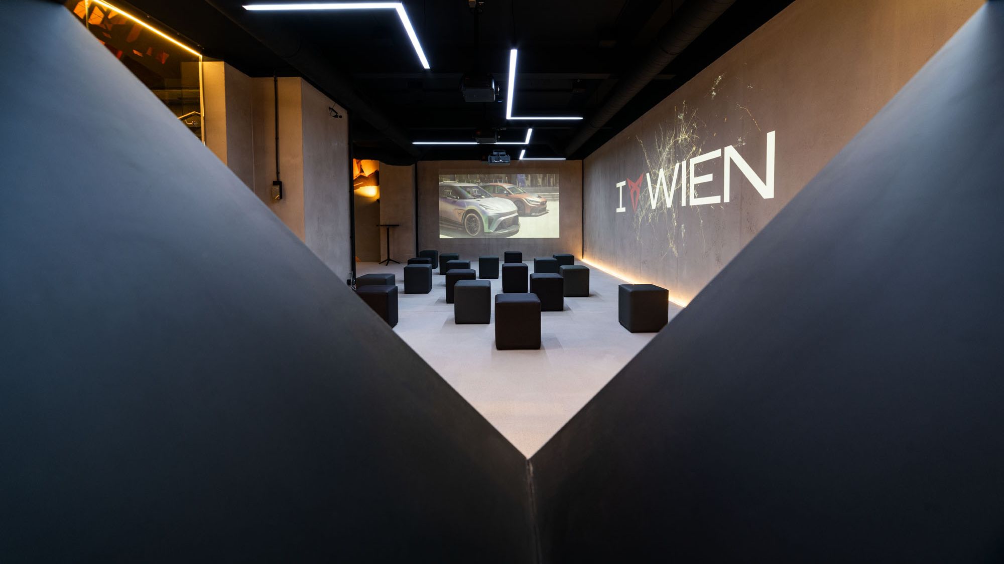 Raum mit Würfel-Sesseln und I CUPRA Wien Logo an der Wand