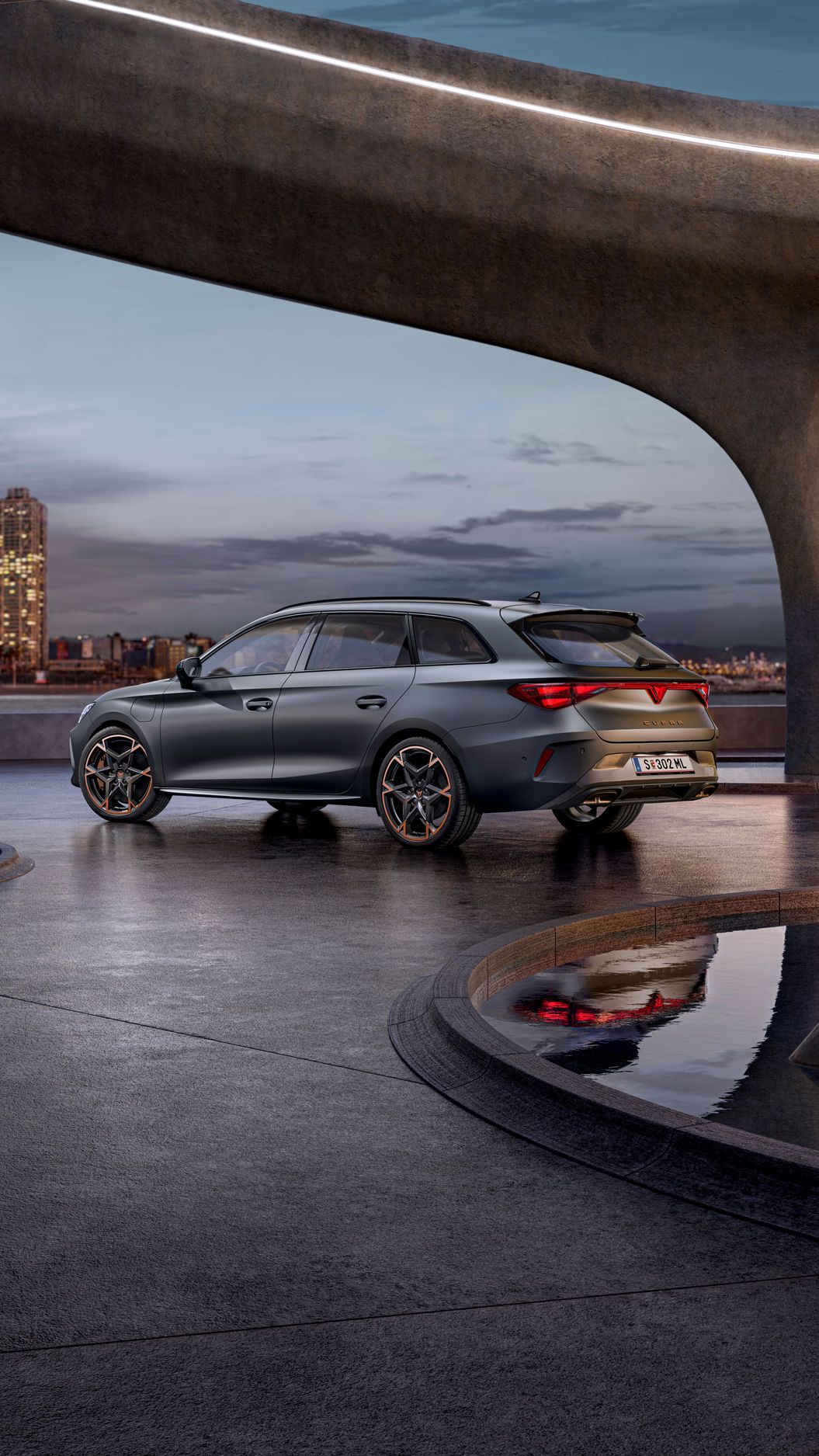 Schräge Seitenansicht von Hinten auf einen grauen CUPRA Leon Sportstourer in einem modernen Parkhaus.