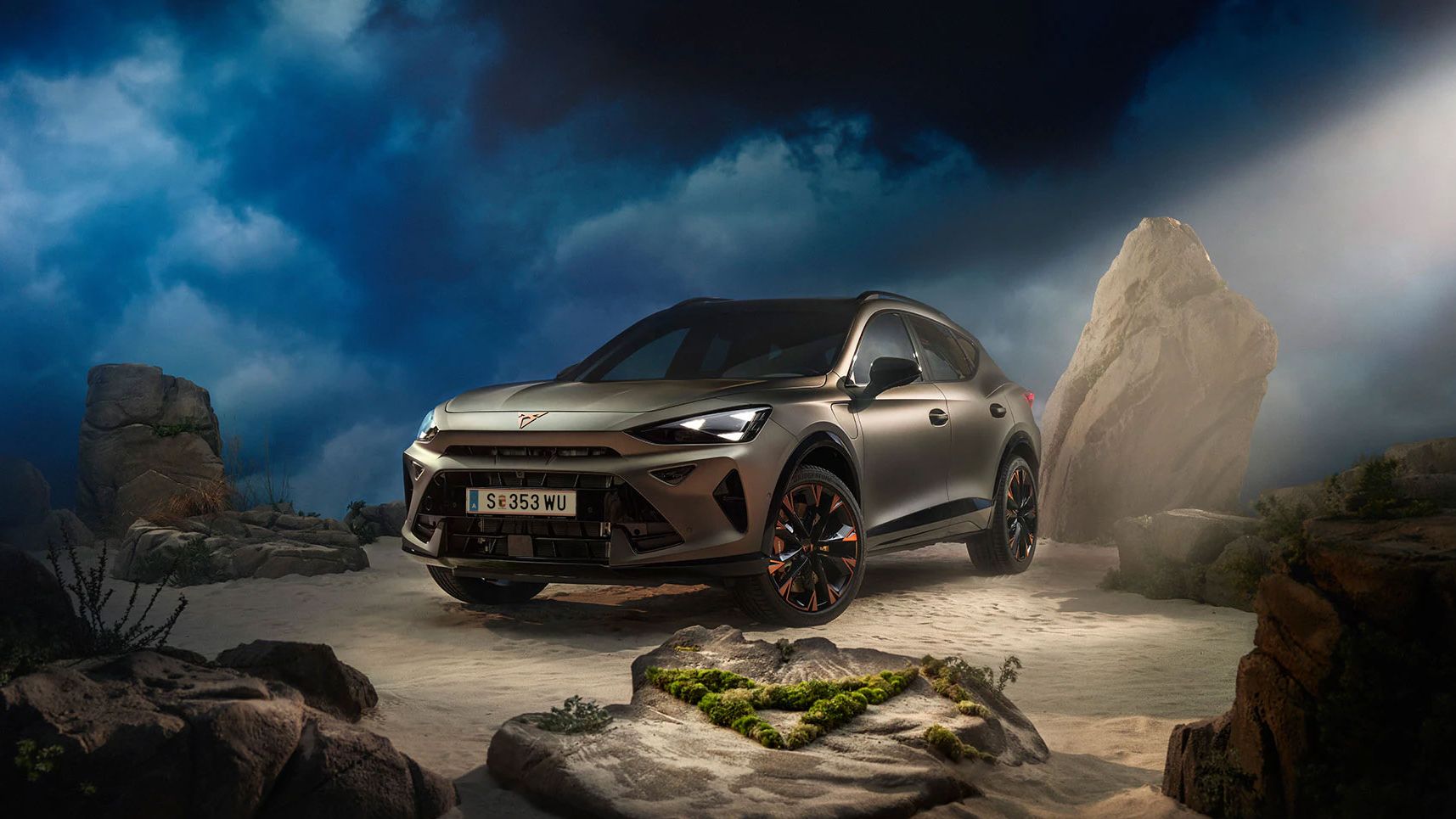 Ein CUPRA Formentor VZ in Bronze steht dramatisch beleuchtet in einer felsigen, nebeligen Landschaft. Eine Lichtstrahl beleuchtet das Fahrzeug und betont seine Konturen. Im Hintergrund sind Felsen und Pflanzen zu sehen.