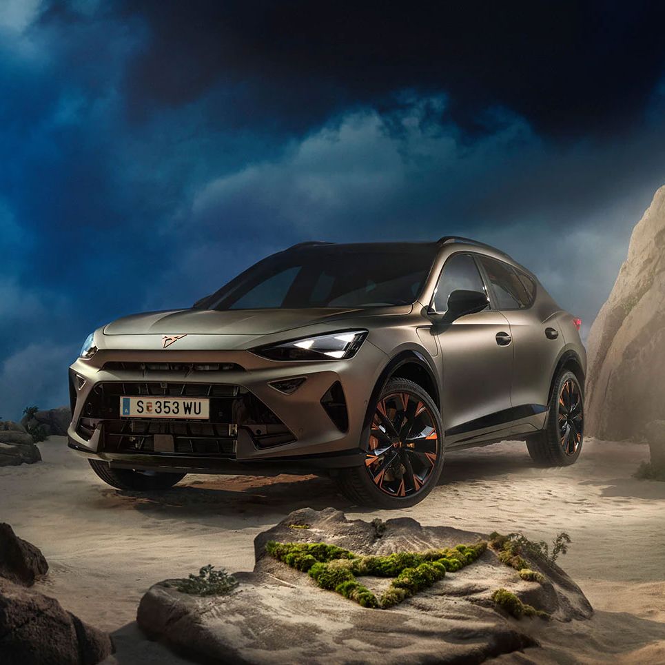 Ein CUPRA Formentor VZ in Bronze steht dramatisch beleuchtet in einer felsigen, nebeligen Landschaft. Eine Lichtstrahl beleuchtet das Fahrzeug und betont seine Konturen. Im Hintergrund sind Felsen und Pflanzen zu sehen.