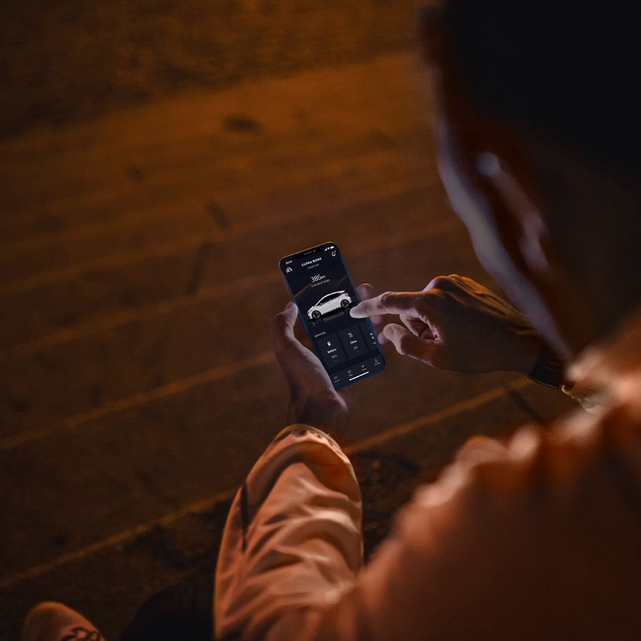 Ein Mann bedient die CUPRA Connect App für den Born auf seinem Smartphone.