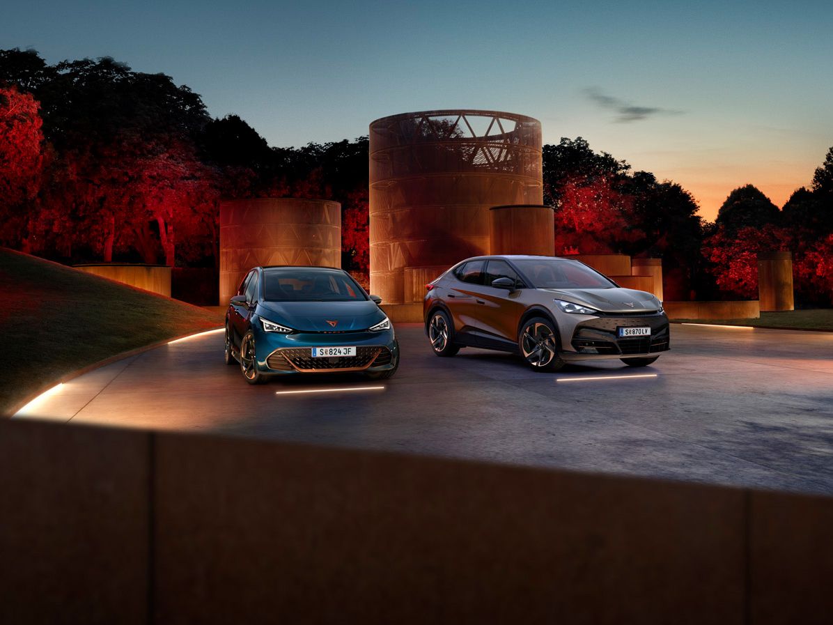 CUPRA Born und Tavascan stehen nebeneinander auf beleuchtetem hintergrund