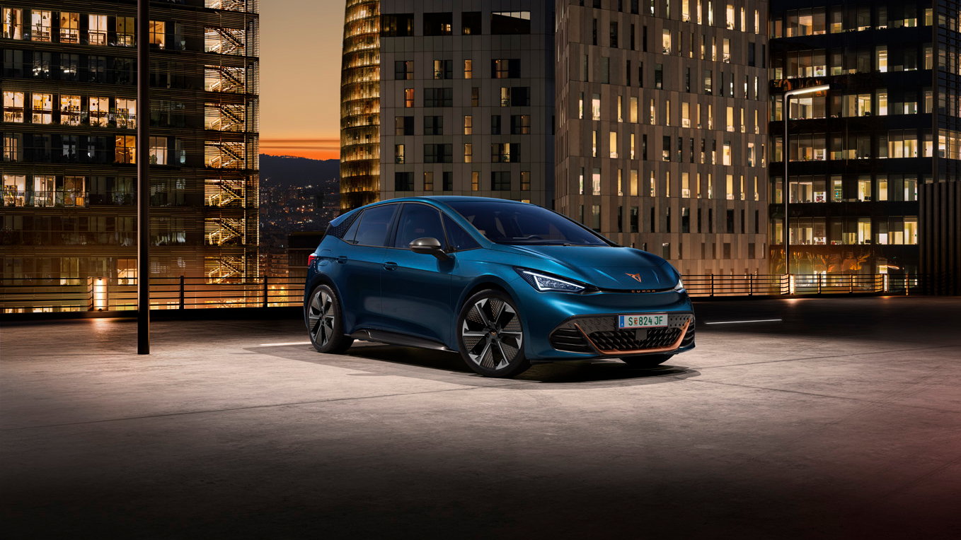 Ein blauer CUPRA Born auf dem Dach eines Parkhauses. Im Hintergrund beleuchtete Gebäude bei Nacht.
