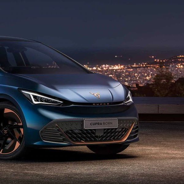 Schräge Frontansicht eines CUPRA Born bei Nacht vor der Silhouette einer Stadt.