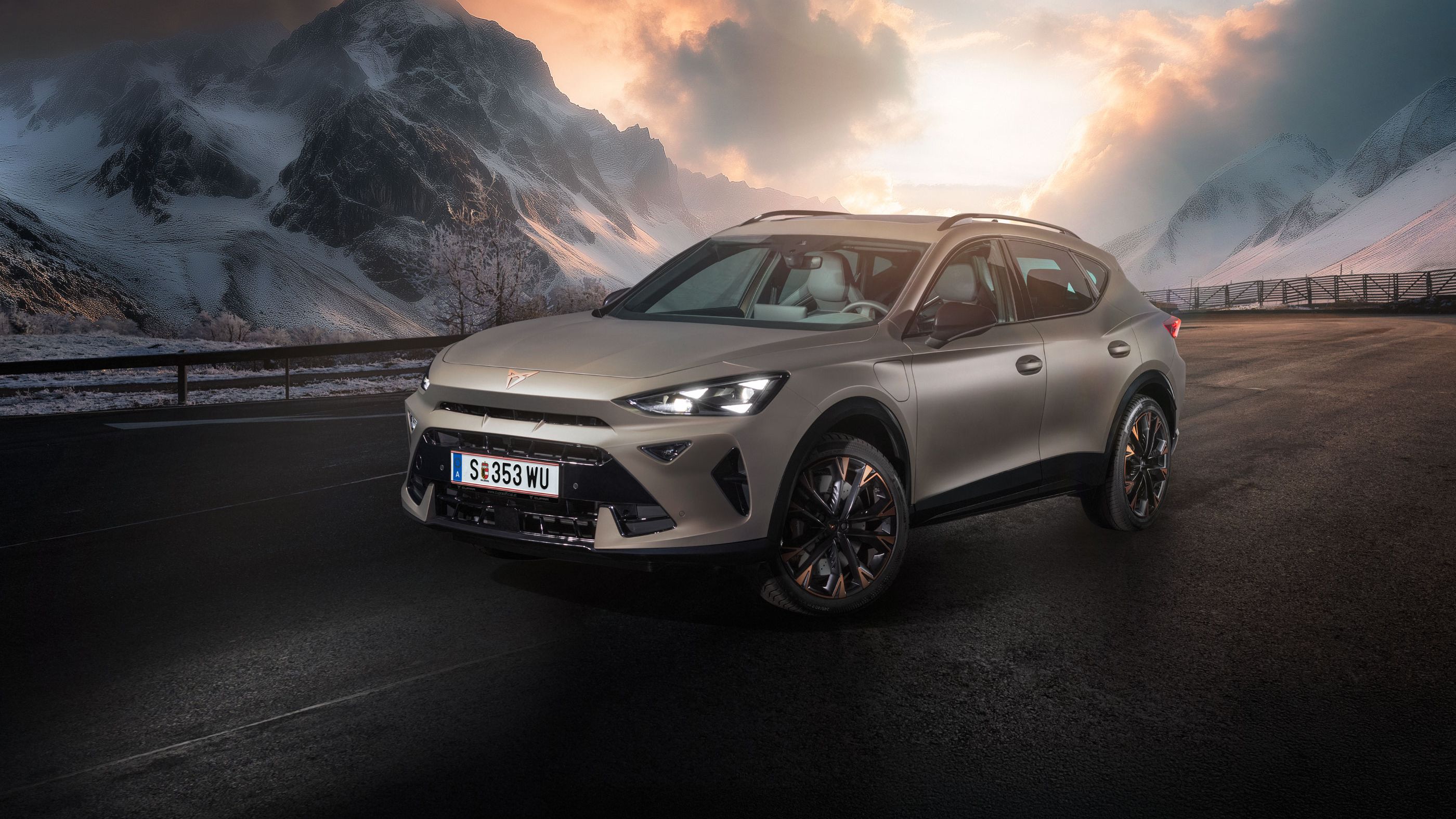 Ein CUPRA Formentor steht auf einer Straße in bergiger Landschaft mit schneebedeckten Gipfeln. Der Himmel ist dramatisch bewölkt. Im Hintergrund scheint die Sonne durch die Wolken.