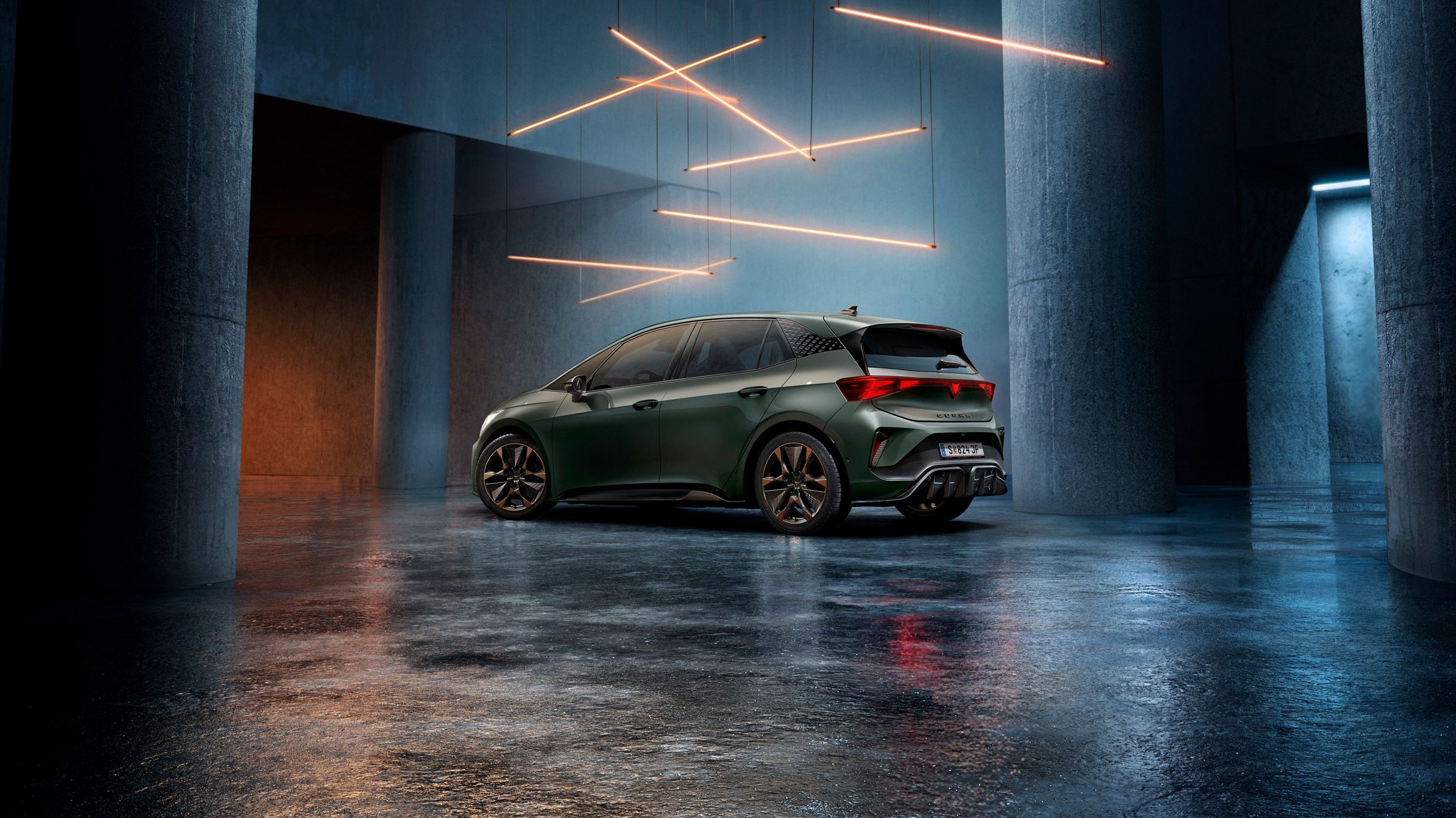 Ein grüner CUPRA Born steht in einem düsteren, industriellen Ambiente mit großen Säulen. Über dem Auto hängen stilvolle, leuchtende LED-Lichter in geometrischen Formen. Der Boden ist glatt und reflektiert das Licht leicht.