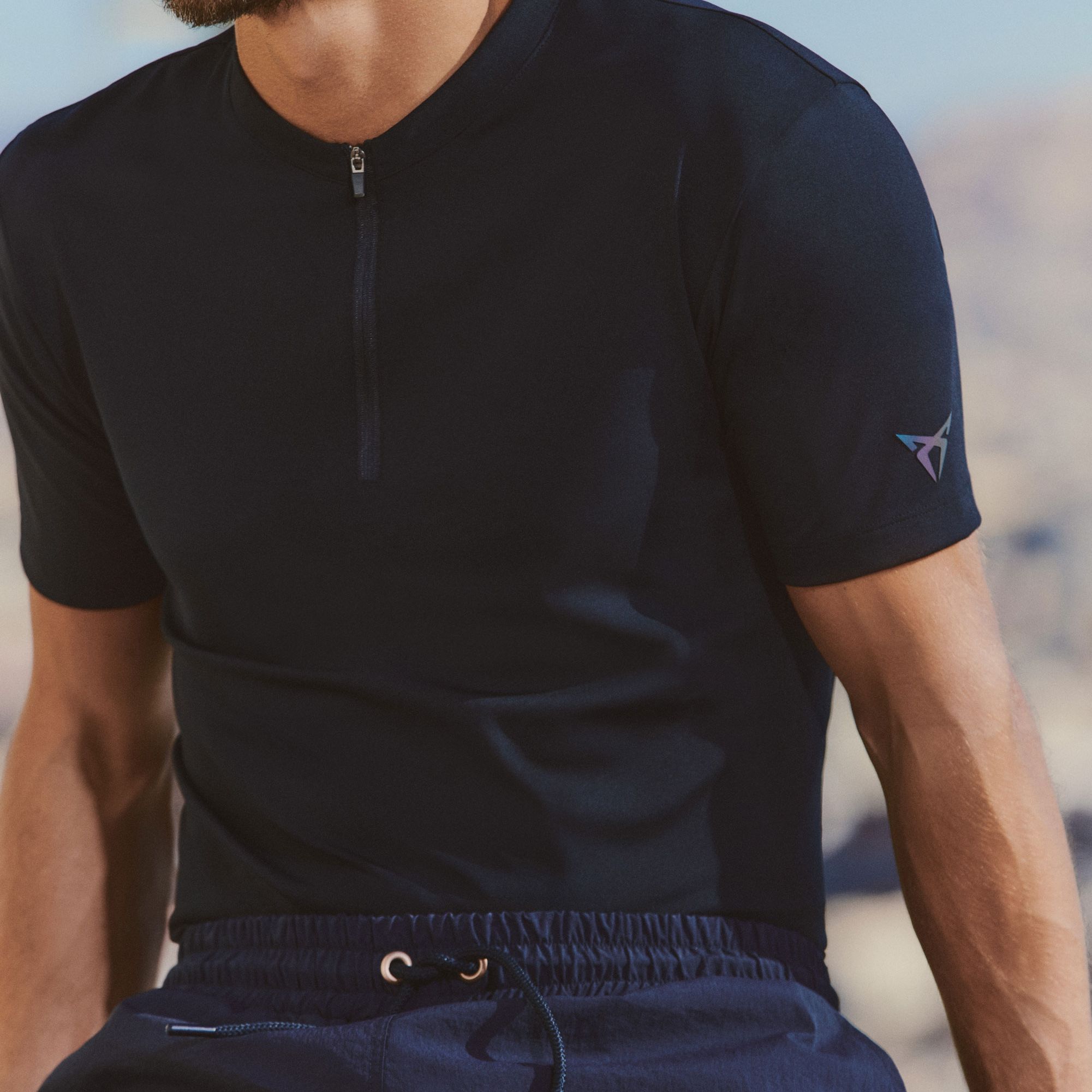 Ein Mann trägt ein blaues Shirt und eine Badehose von CUPRA Lifestyle