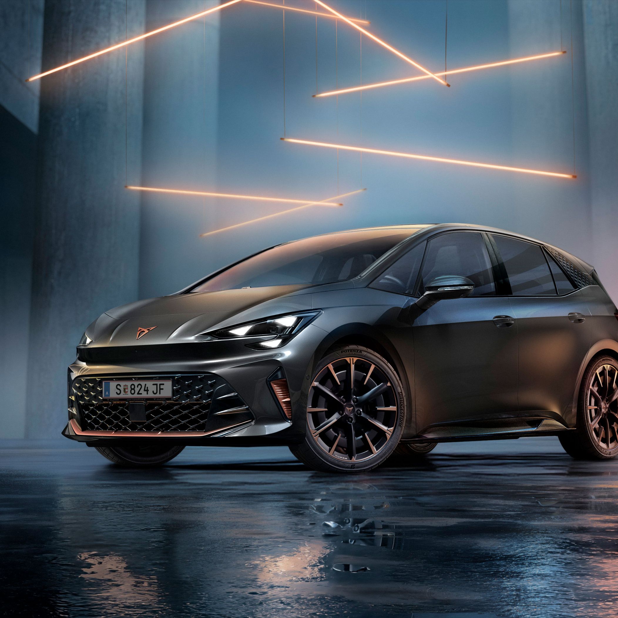 Ein grauer CUPRA Born steht in einer modernen, dunklen Umgebung mit vertikalen Säulen und leuchtenden LED-Streifen. Der Boden ist glänzend und reflektiert das Fahrzeug sowie die Beleuchtung. Das Auto wirkt kraftvoll und elegant.