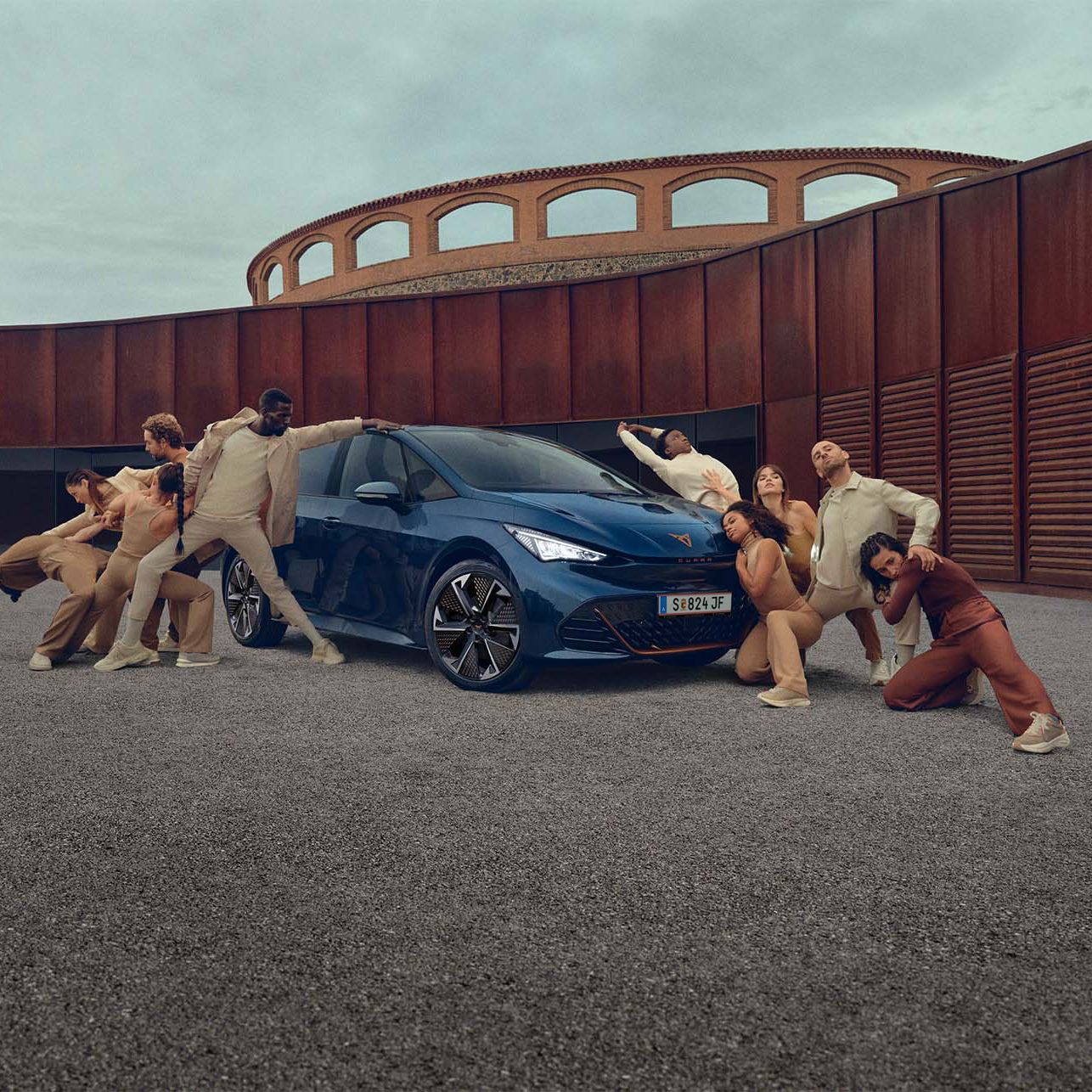 Ein blauer CUPRA Born steht auf einem Platz, mehrere Personen befinden sich links und rechts neben dem Fahrzeug.
