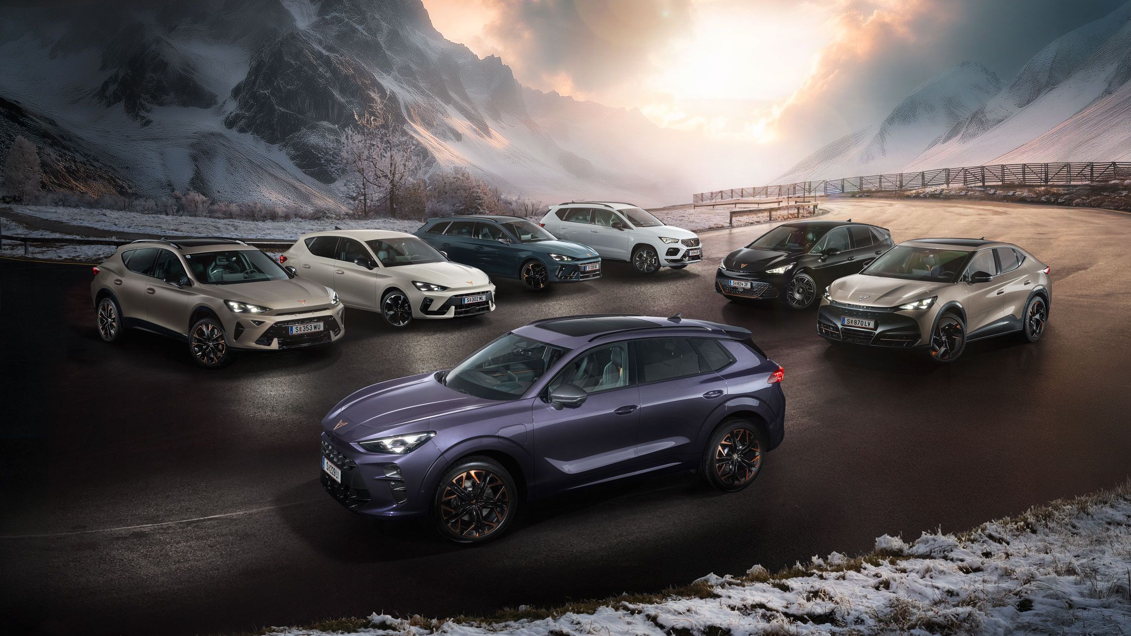 Eine Gruppe von CUPRA Fahrzeugen stehen auf einer verschneiten Straße vor einer malerischen Berglandschaft bei Sonnenuntergang. Es sind verschiedene Modelle in unterschiedlichen Farben. Im Hintergrund sind hohe, schneebedeckte Berge und dramatische Wolkenformationen zu sehen.