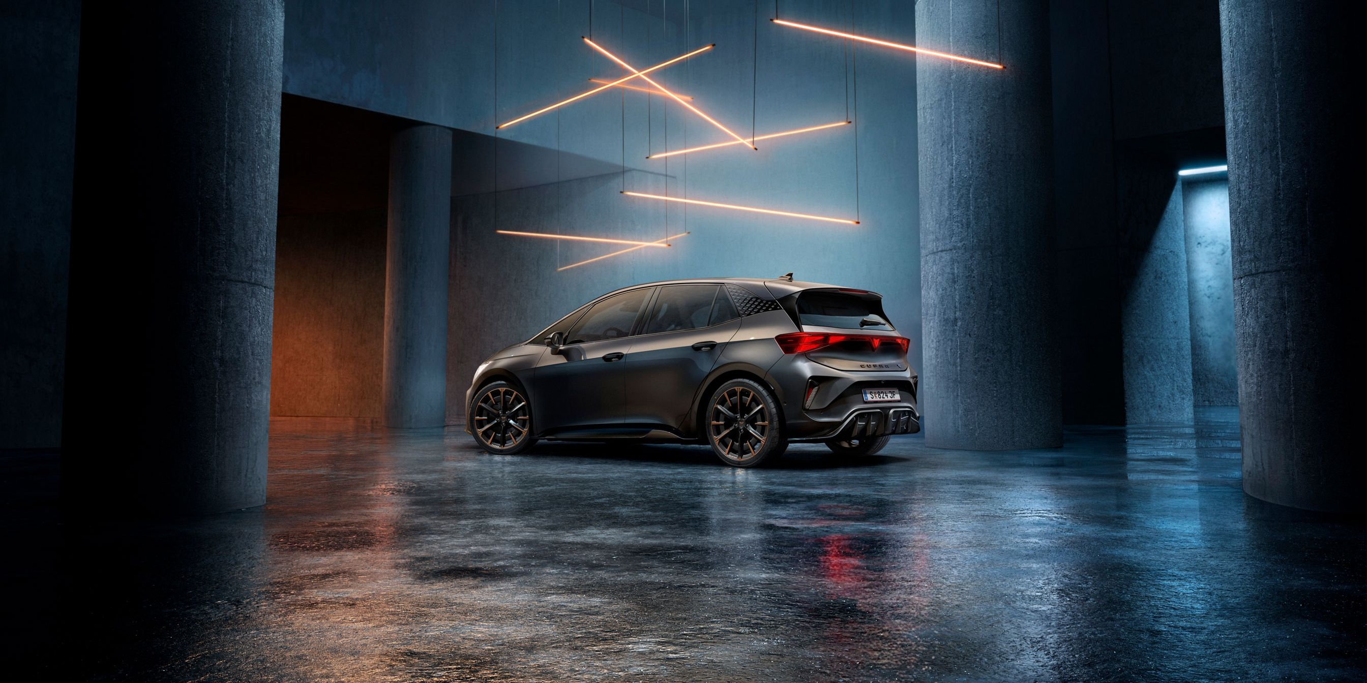 Ein CUPRA Born steht in einem stilvoll beleuchteten, industriellen Raum mit Betonwänden und -säulen. Von der Decke hängen mehrere lineare Lichtquellen, die ein elegantes Ambiente schaffen. Das Fahrzeug ist rückseitig zu sehen und reflektiert das Licht auf dem glänzenden Boden.