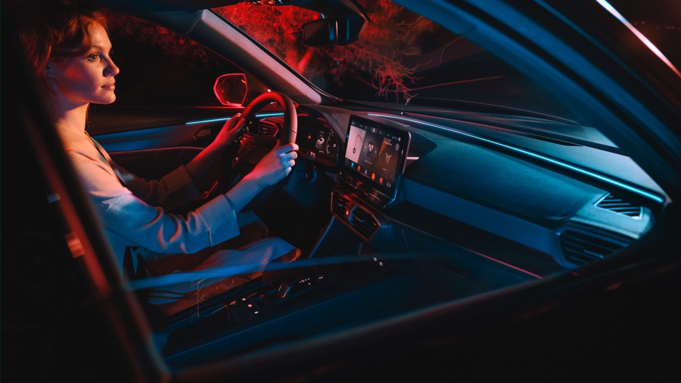 Eine Frau sitzt im Auto mit den Händen am Lenkrad.