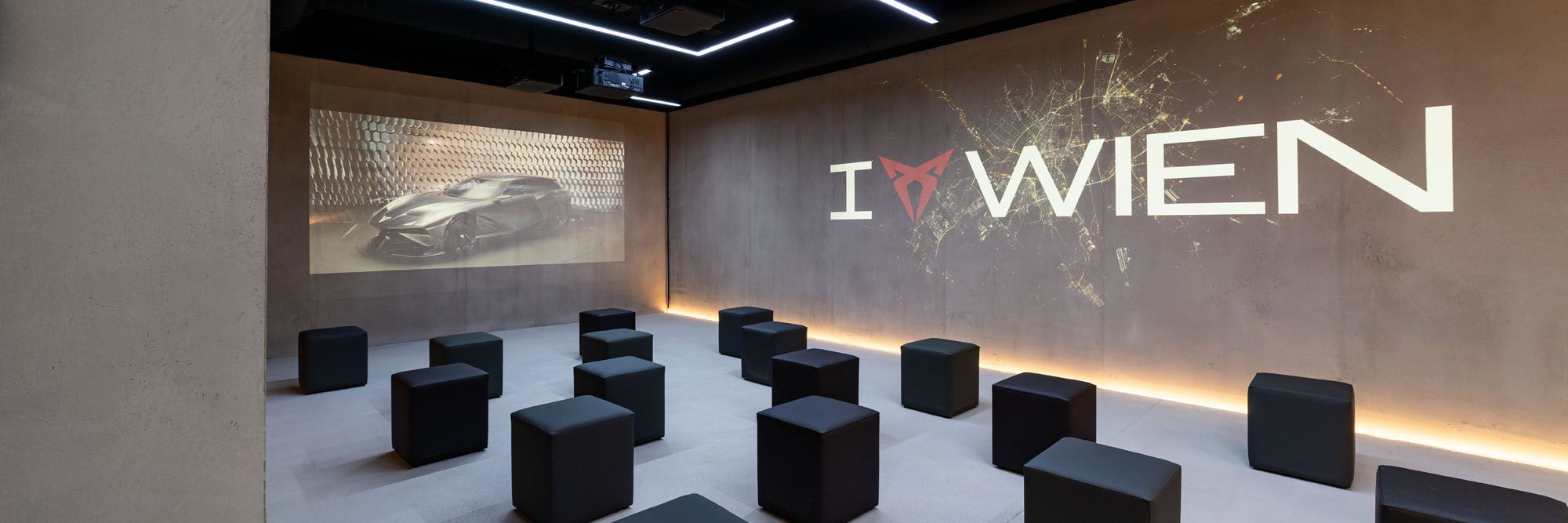 Raum mit Würfel-Sesseln und I CUPRA Wien Logo an der Wand
