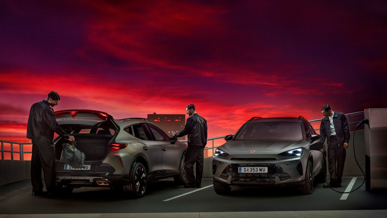 Vorder- und Rückansicht von zwei parkenden CUPRA Formentor. Ein Fahrzeug wird gerade aufgeladen. Beim zweiten legt ein Mann eine Reisetasche in den Kofferraum.