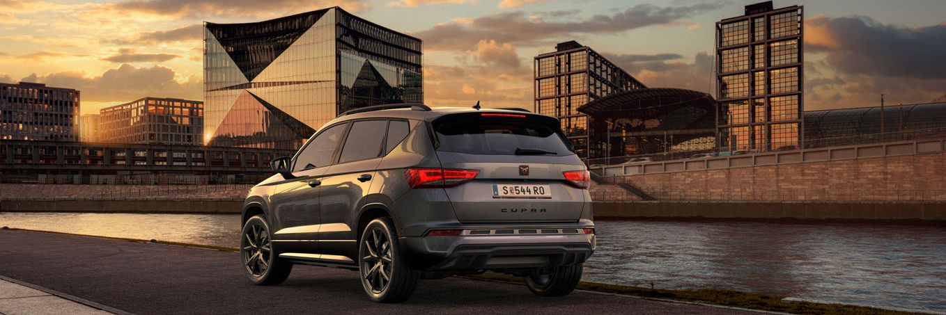 Heckansicht des CUPRA Ateca SUVs bei Sonnenuntergang, mit Fokus auf den neuen, niedrigeren Frontgrill mit Luftkappen und den neuen Heckdiffusor, die beide das äußere Design verstärken und die Aerodynamik optimieren.