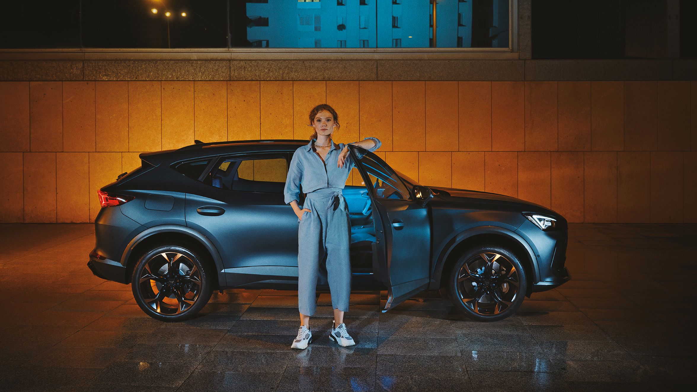 CUPRA Formentor bei Nacht, eine Frau steht davor