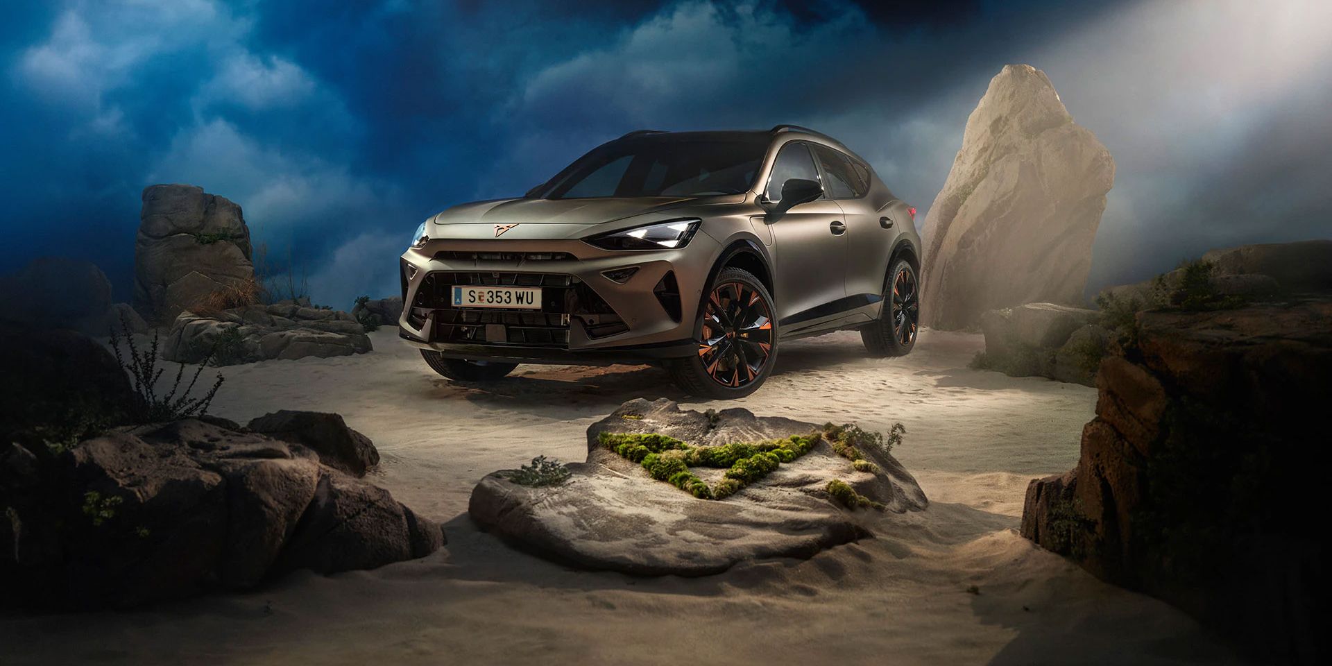 Ein CUPRA Formentor VZ in Bronze steht dramatisch beleuchtet in einer felsigen, nebeligen Landschaft. Eine Lichtstrahl beleuchtet das Fahrzeug und betont seine Konturen. Im Hintergrund sind Felsen und Pflanzen zu sehen.