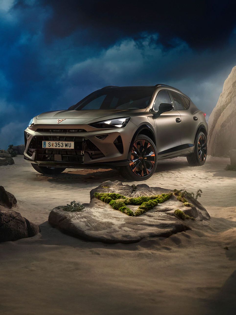 Ein CUPRA Formentor VZ in Bronze steht dramatisch beleuchtet in einer felsigen, nebeligen Landschaft. Eine Lichtstrahl beleuchtet das Fahrzeug und betont seine Konturen. Im Hintergrund sind Felsen und Pflanzen zu sehen.
