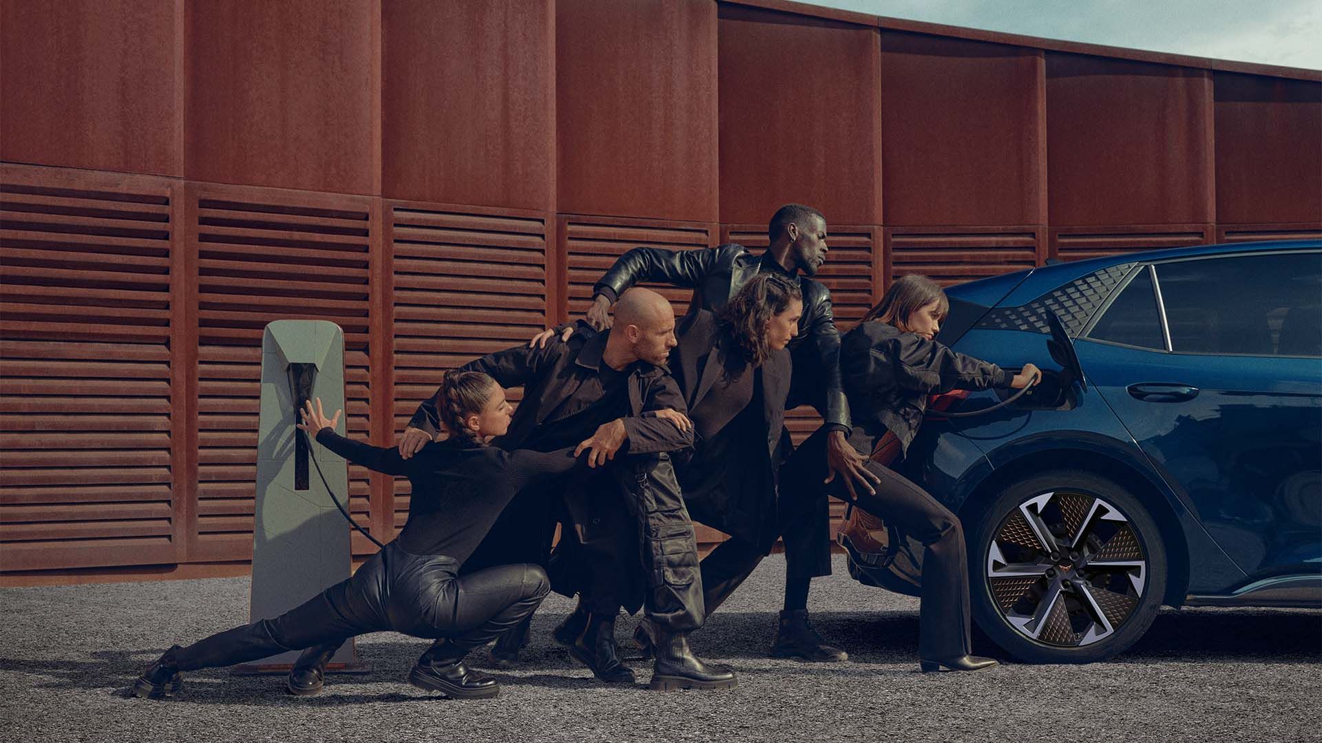 Eine Gruppe von Personen beim Aufladen eines blauen CUPRA Born an der Ladesäule.