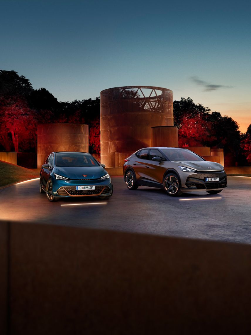 CUPRA Born und Tavascan stehen nebeneinander auf beleuchtetem hintergrund
