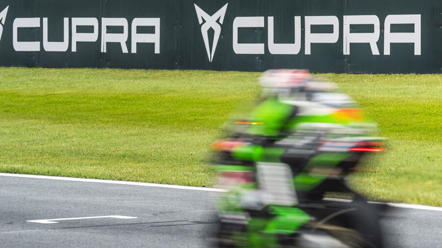 Ein Motorrad in Fahrt auf einer Rennstrecke. Im Hintergrund das CUPRA Logo und Schriftzug.