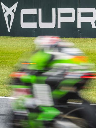 Ein Motorrad in Fahrt auf einer Rennstrecke. Im Hintergrund das CUPRA Logo und Schriftzug.