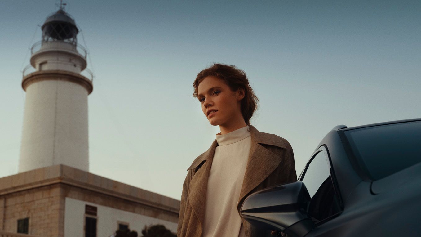 Eine Frau und ein CUPRA Formentor vor einem Leuchtturm.