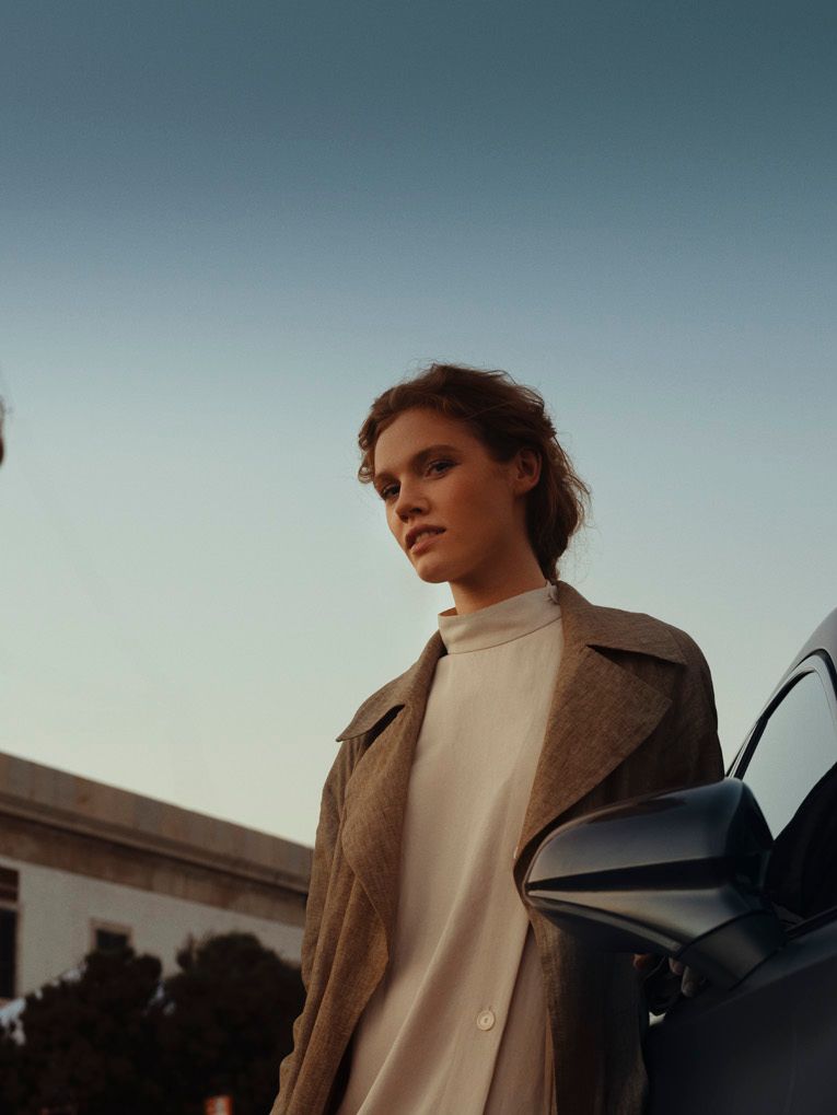 Eine Frau und ein CUPRA Formentor vor einem Leuchtturm.