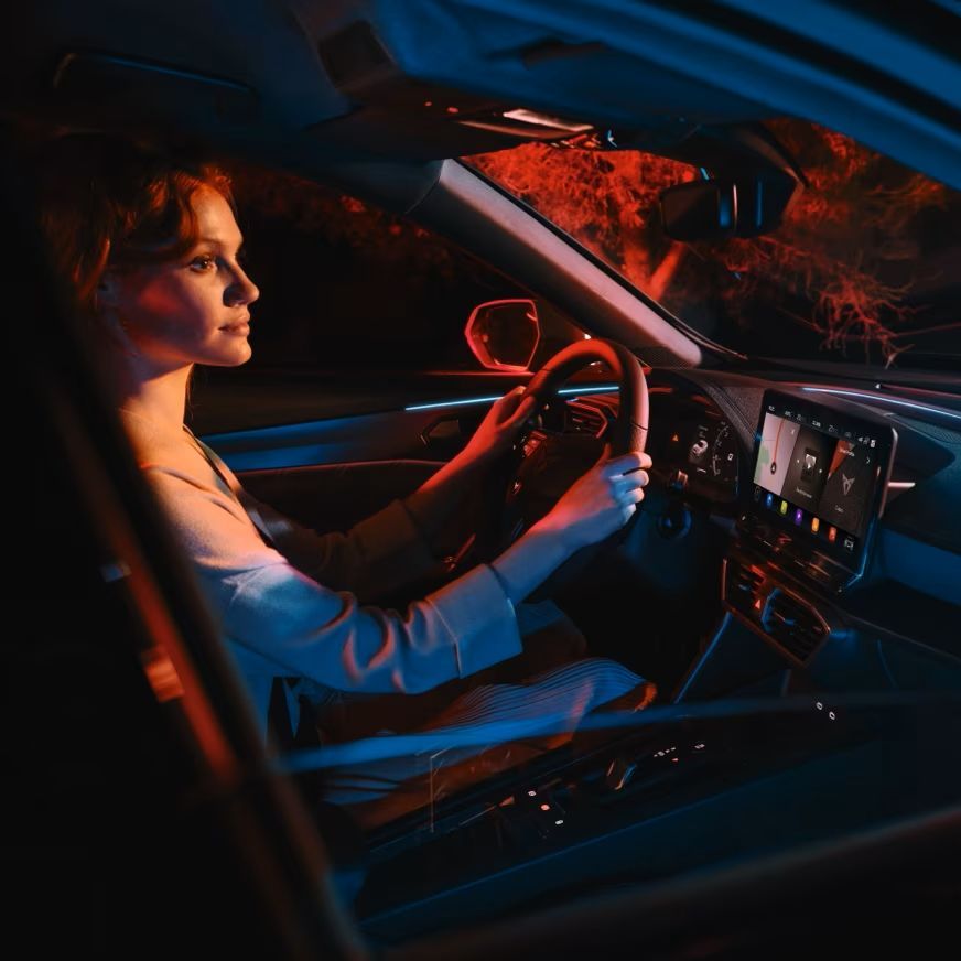 Eine Frau lenkt einen CUPRA und spricht mit dem CUPRA Connect Sprachassistent