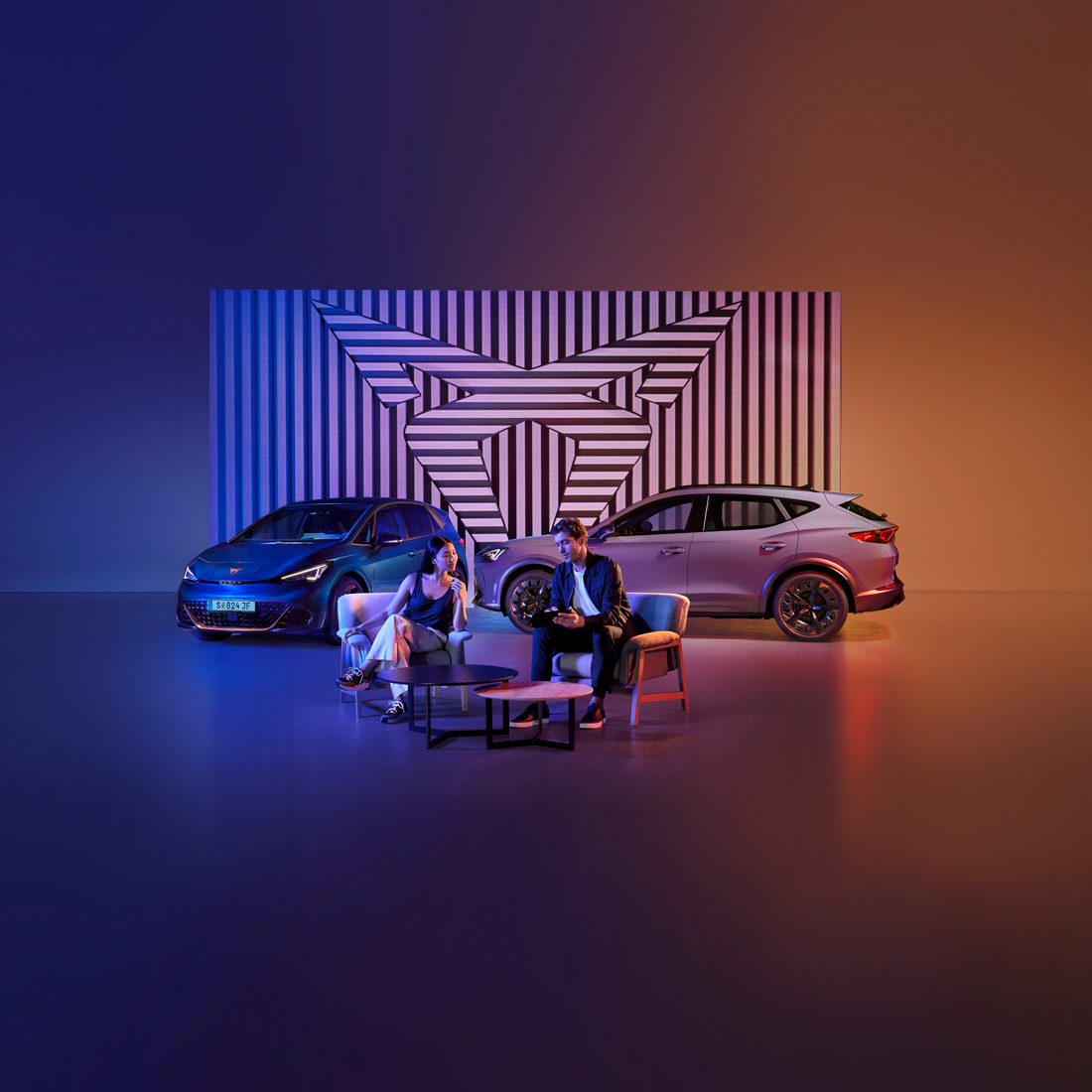 Mann und Frau sitzen vor CUPRA Modellen am Tisch