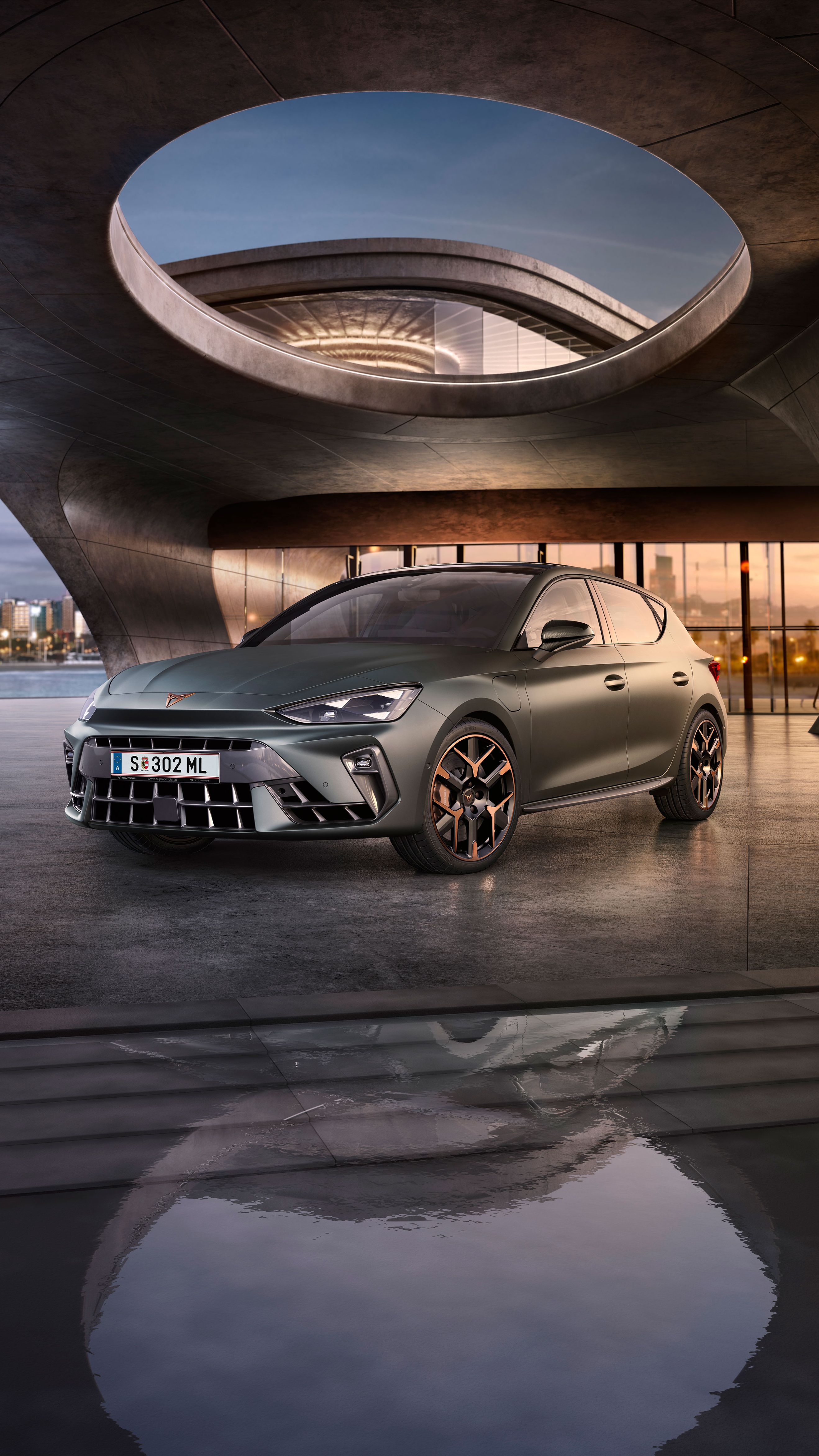 Schräge Vorderansicht eines grauen CUPRA Leon, der in einem modernen Parkhaus parkt.